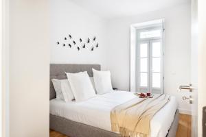 um quarto branco com uma cama grande e almofadas brancas em FLH Vila Rosário Cosy Flat II em Lisboa