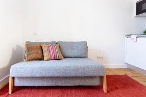 um sofá cinzento com almofadas num tapete vermelho em FLH Vila Rosário Cosy Flat II em Lisboa