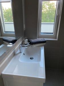 La salle de bains est pourvue d'un lavabo blanc et d'un miroir. dans l'établissement Aranyhíd Apartman Balatonalmádi, à Balatonalmádi