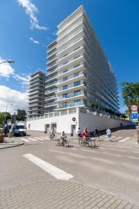 Eine Gruppe von Leuten, die mit einem hohen Gebäude Fahrrad fahren in der Unterkunft Stylish Apartment Balticus 15 with Air Conditioning by Noclegi Renters in Misdroy