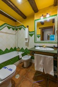 Un baño con lavabo, inodoro y espejo. en Hotel Rural Almazara, en Frigiliana