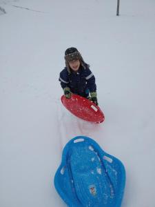a young child playing in the snow with a snowboard at Kwatera u Somsiada -Apartament in Muszyna
