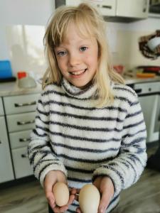 a little girl holding three eggs in her hands at Kwatera u Somsiada -Apartament in Muszyna