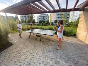 kobieta stojąca obok stołu do ping ponga w obiekcie Relax Apartman w Siófoku