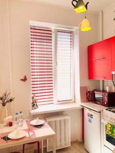 マグニトゴルスクにあるRed Roomの赤いキャビネットとテーブル、窓付きのキッチン