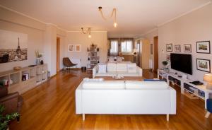 a living room with a white couch and a tv at Athens Airport Lodge in Spáta