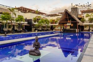 una piscina en un complejo con una estatua en el medio en Aldea Thai by Mistik Vacation Rentals, en Playa del Carmen