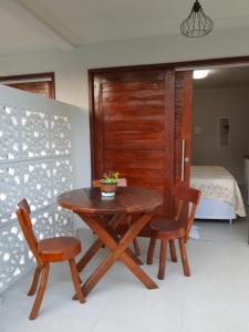 a wooden table and two chairs in a room with a bed at Pousada Paraíso dos Milagres in São Miguel dos Milagres