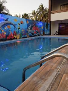una piscina con un mural en la pared en Pousada Paraíso dos Milagres en São Miguel dos Milagres