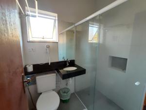 a bathroom with a toilet and a sink and a shower at Pousada Casa na Praia in Ubatuba