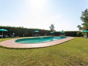 a swimming pool with chairs and umbrellas in a yard at Apartment in Tuscany near Lake Trasimeno in Tuoro sul Trasimeno