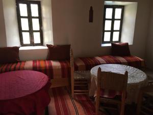 a room with a couch and a table and windows at Maison D'hôtes Dar Afra in Aït Ziri