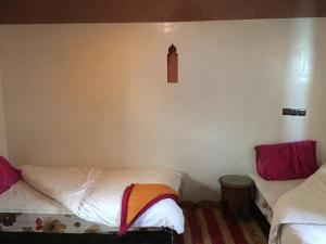 um quarto com duas camas e uma parede com um relógio em Maison D'hôtes Dar Afra em Aït Ziri