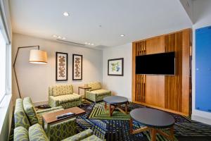 a hotel room with a couch and chairs and a flat screen tv at Holiday Inn Express - Evansville, an IHG Hotel in Evansville