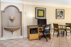 a room with a desk with a computer and a sink at La Quinta Inn Tampa Airport Stadium Westshore in Tampa