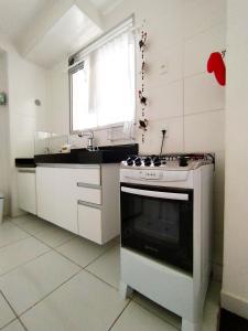 a white kitchen with a stove and a window at MAR & SOL Apartamentos I - Free Wi-Fi in Rio das Ostras