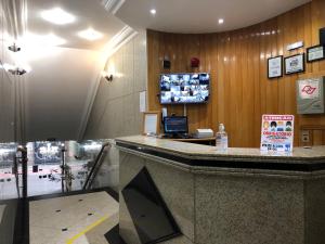 a hotel lobby with a counter with a tv on the wall at Paissandú Palace Hotel - Próximo às ruas 25 de Março, Sta Ifigênia e regiões do Brás e Bom Retiro in Sao Paulo