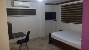 ein Schlafzimmer mit einem Bett, einem Schreibtisch und einem Stuhl in der Unterkunft Hotel Fika Guayaquil in Guayaquil