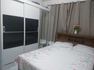 a bedroom with a bed and a window with a vase of flowers at Casa para fins de semana/feriado in São Sebastião