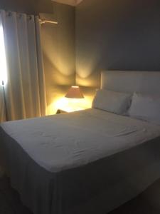 een slaapkamer met een wit bed en een lamp bij Hotel Maracas Punta Cana in Punta Cana