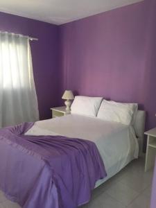 1 dormitorio con paredes moradas y 1 cama blanca en Hotel Maracas Punta Cana, en Punta Cana