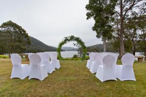 a row of white chairs sitting on top of a grass covered field at Tullah Lakeside Lodge in Tullah