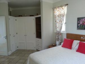 a bedroom with a white bed with red pillows at Los Balcones in Sosúa +22 photos