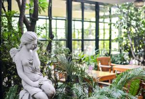 a statue of a woman talking on a cell phone in a garden at Grand Howard Hotel Bangkok in Bangkok