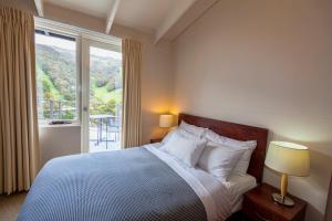 a bedroom with a bed and a large window at The Denman Hotel in Thredbo in Thredbo