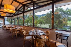 a restaurant with tables and chairs and large windows at The Denman Hotel in Thredbo in Thredbo
