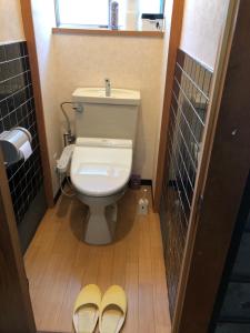a bathroom with a toilet and two pairs of slippers at Kanazawa-Hachitabi Sennichi in Kanazawa