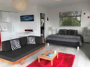 sala de estar con sofá negro y mesa en Sea La Vie - Waiheke Island Luxury Accommodation, en Onetangi