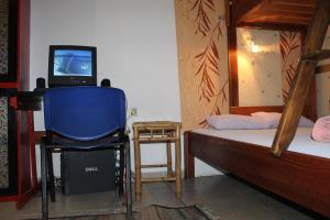 1 dormitorio con 1 cama y TV en una silla en Tash Inn Hostel, en Belgrado