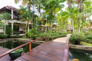 a wooden walkway leading to a resort with a pond at Khaolak Bayfront Resort in Khao Lak