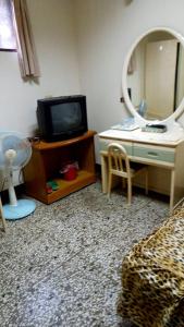Zimmer mit einem TV und einem Tisch mit einem Spiegel in der Unterkunft 東海旅社 有匯款才會留房喔 in Shuili