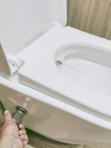 una persona tiene una bottiglia d'acqua accanto a un bagno di Abbracci leandra Rooms a Civitavecchia