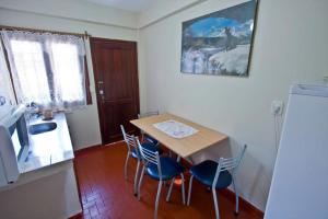 cocina con mesa, sillas y nevera en Alecrin Apart en Puerto Iguazú
