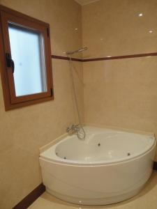 La salle de bains est pourvue d'une baignoire blanche et d'une fenêtre. dans l'établissement Casa de Xerta, à Xerta