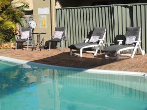 
a patio area with chairs, tables, and umbrellas at Argyle Terrace Motor Inn in Batemans Bay
