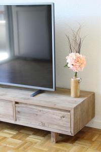 a vase with a flower on a wooden tv stand at Ferien in Glarus in Glarus