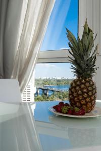 um ananás num prato numa mesa em frente a uma janela em Exquisite panoramic views apartment Dnipro embankment em Kiev