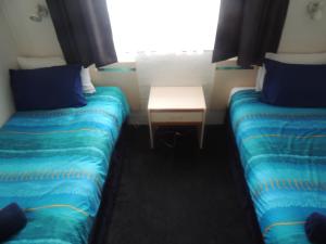 
two beds in a small room with a window at Argyle Terrace Motor Inn in Batemans Bay
