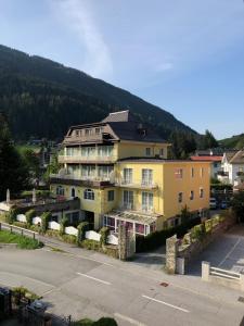 um grande edifício amarelo com uma montanha ao fundo em Hotel Lindenhof em Bad Gastein