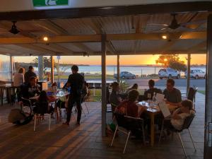 a group of people sitting at tables in a restaurant at Waterside House Kalbarri in Kalbarri