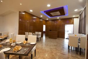 a dining room with tables and chairs and a tv at crystal inn in Chikmagalūr