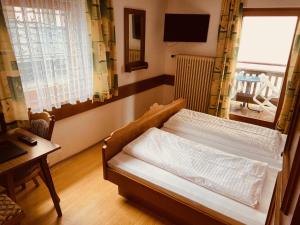 a bedroom with a bed and a table and a window at Pension Eder - Joker card included in summer in Saalbach-Hinterglemm