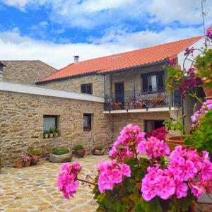 uma casa de pedra com flores cor-de-rosa à frente. em Casa D'Augusta - Agroturismo em Miranda do Douro
