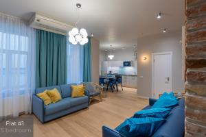 a living room with two blue couches and a kitchen at Dandelion Apartments Brīvības in Rīga