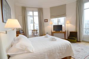 um quarto com uma cama branca e uma televisão em Champs Elysees em Paris