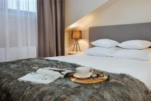 een hotelkamer met een bed met een kopje koffie en een boek bij Noclegi Pod Sokołem in Sokółka